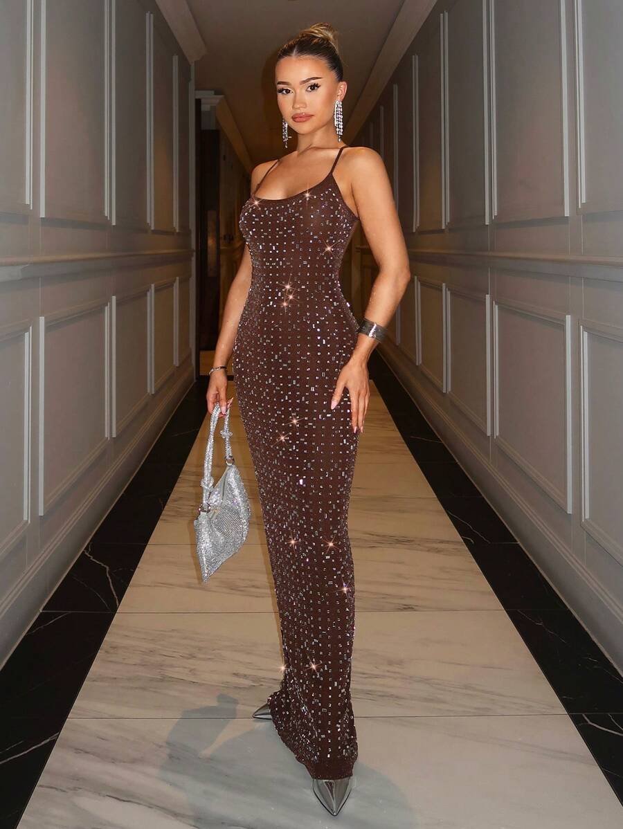 Front three-quarter view of brown rhinestone maxi gown styled with metallic evening accessories