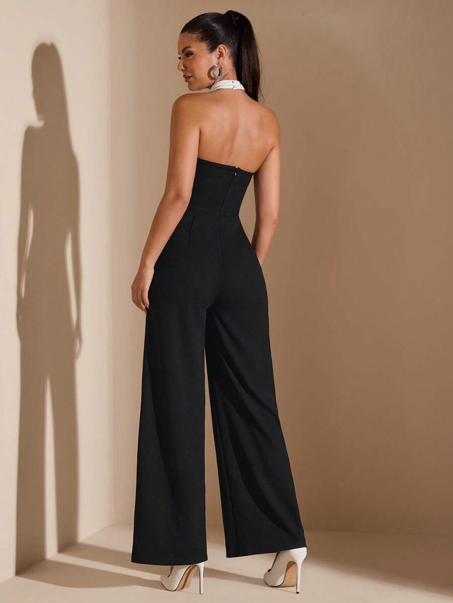 Front full-length view of black and white colorblock halter jumpsuit with wide legs in studio styling