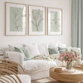 Sage green botanical print set above a white living room sofa