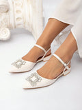 Front three-quarter view of white rhinestone slingback flats worn in a studio setting