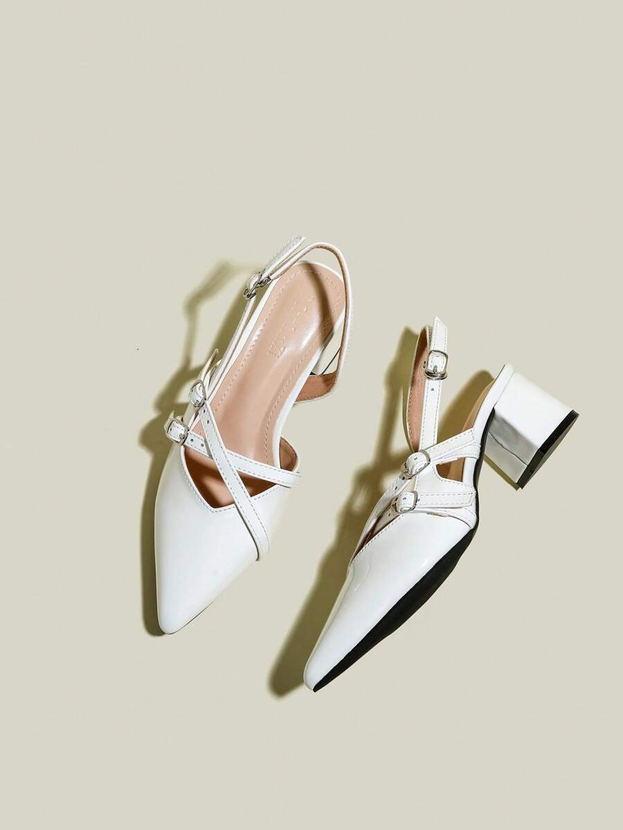 White patent pointed-toe slingback pumps with crisscross buckle straps and chunky block heels, front flat lay