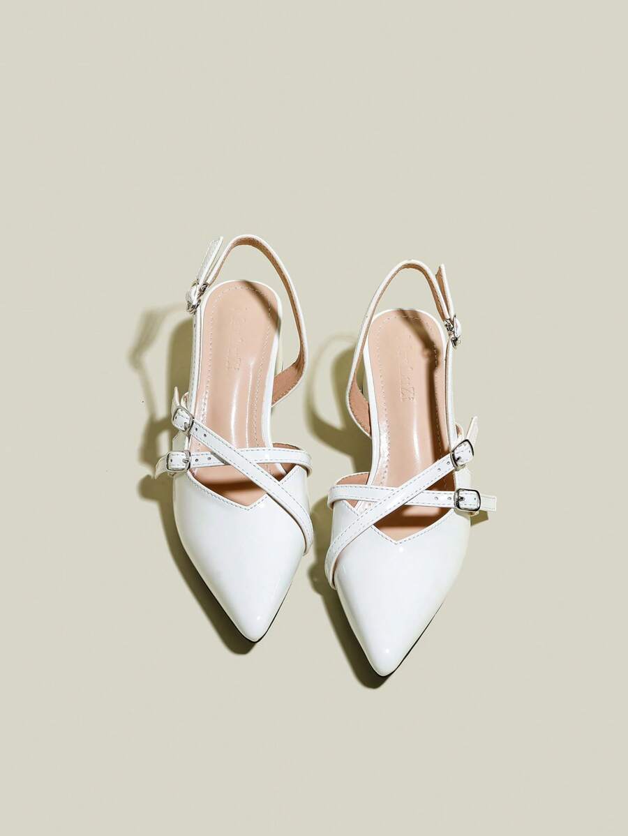 White patent pointed-toe slingback pumps with crisscross buckle straps and chunky block heels, front flat lay