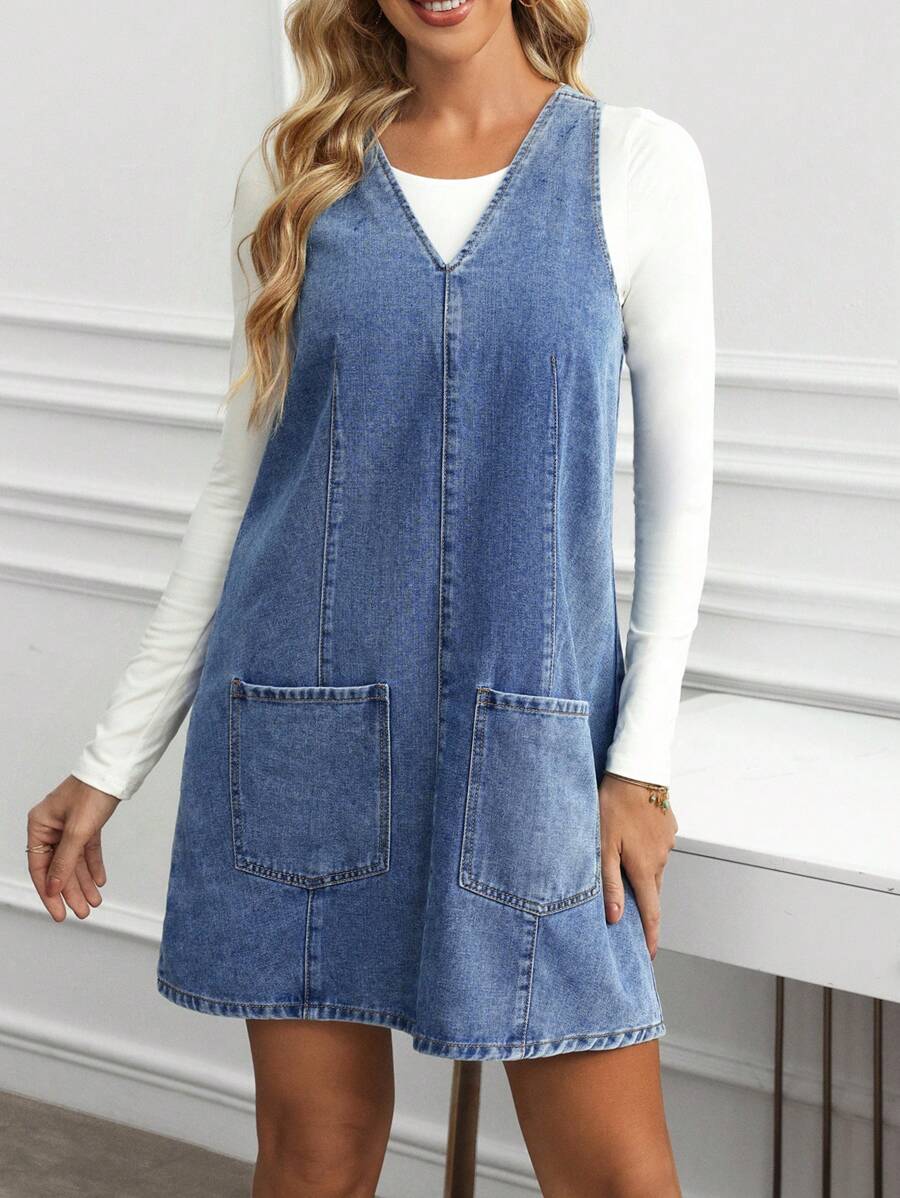 Full front view of medium blue A-line denim mini dress with two oversized patch pockets