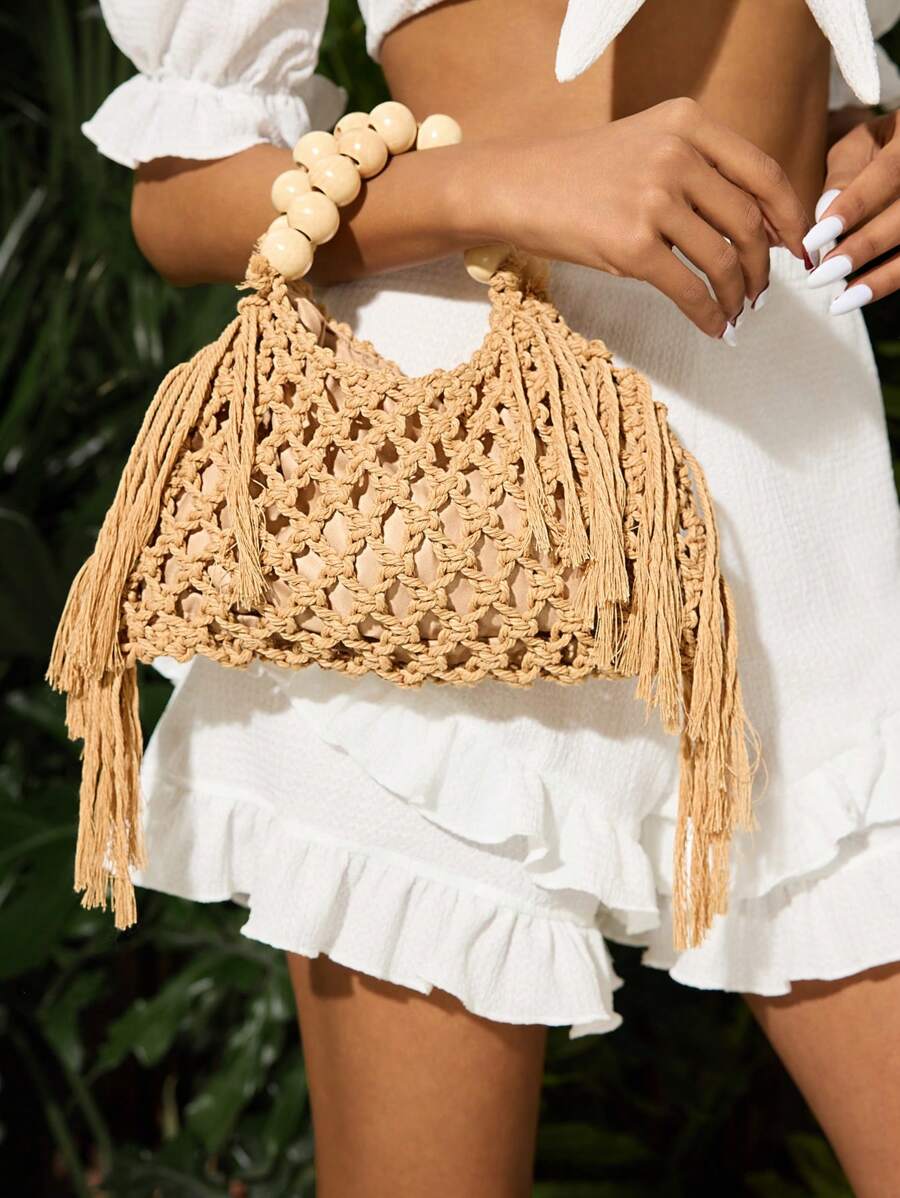 Natural beige crochet beach bag with bead handle and long fringe held by model
