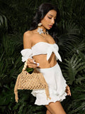 Beige crochet beach bag held by model with hollow knit tassels and round bead handle