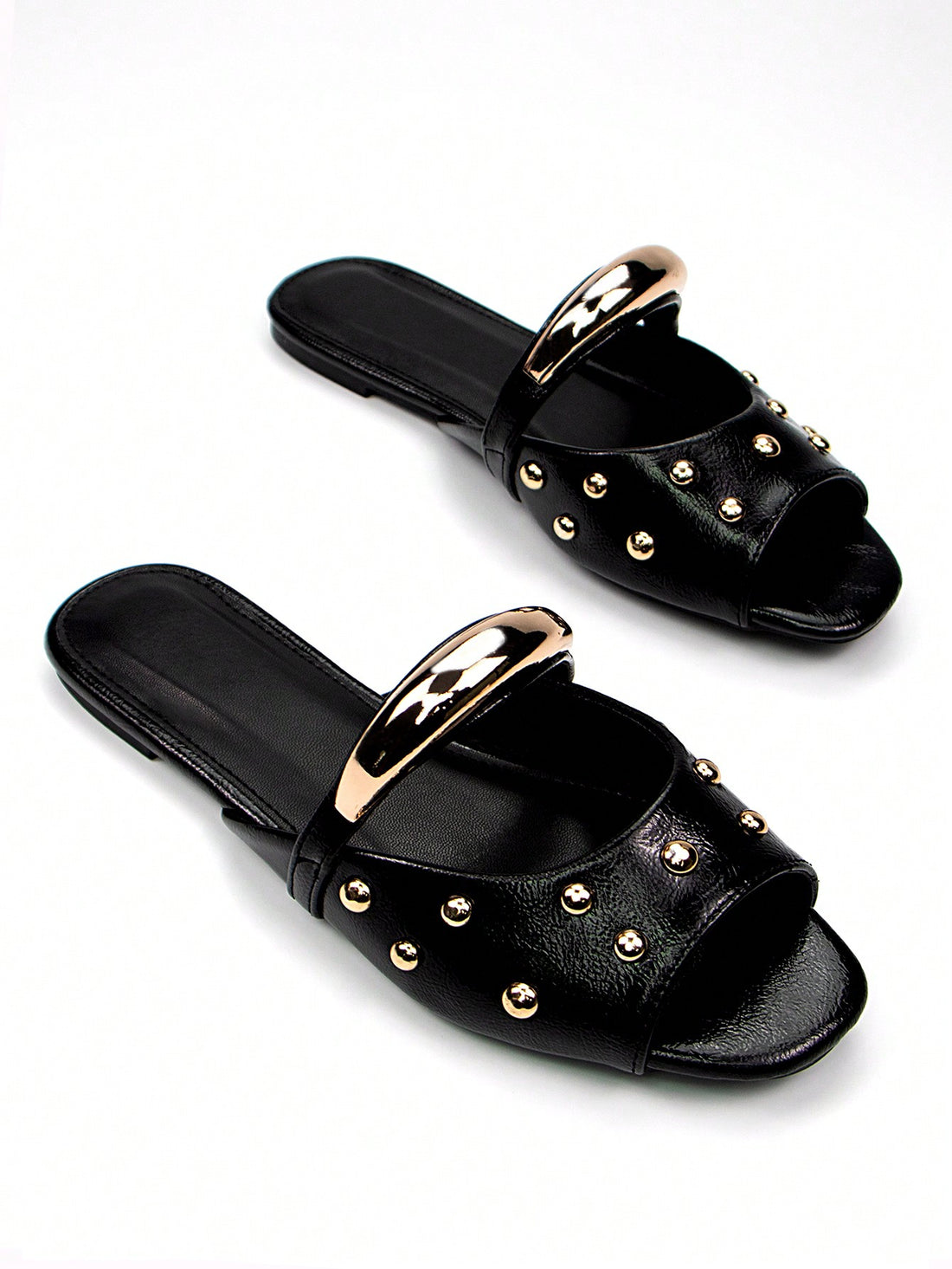 Elevate your everyday footwear with these sophisticated black patent mule slides, featuring a striking gold buckle accent that adds refined elegance to any casual ensemble. The sleek patent leather finish delivers a polished look while maintaining the comfort of a slip-on design, making them ideal for effortless transitions from home to errands. The flat sole provides all-day wearability without sacrificing style, while the minimalist silhouette pairs seamlessly with jeans, dresses, or relaxed separates. Pe
