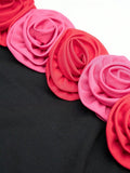 Close view of red and pink fabric rose appliqués on black strapless dress neckline