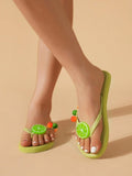 Front on-foot view of light green fruit charm flip-flops in a studio setting