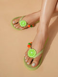 Diagonal on-foot view of light green fruit sandals on a beige studio floor