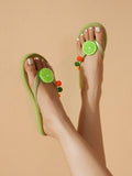 High top view of green thong sandals with lime and orange fruit charms