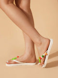 Low side view of white thong flip-flops with lime and multicolor fruit charms