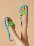 High top view of blue fruit charm thong sandals on a neutral studio floor