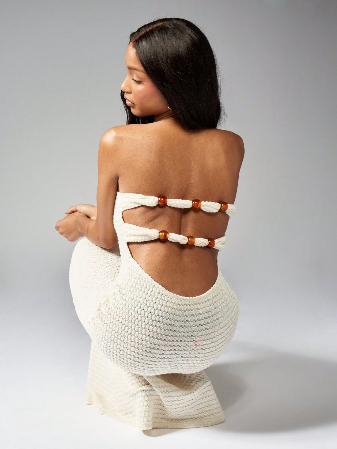 Step into summer with this Crochet Knit Bandeau Maxi Dress. Featuring intricate bead detailing, a playful cut-out back, and a flowy flared hem, this dress will have you turning heads at any event. Show off your unique style and stay cool in this must-have piece.