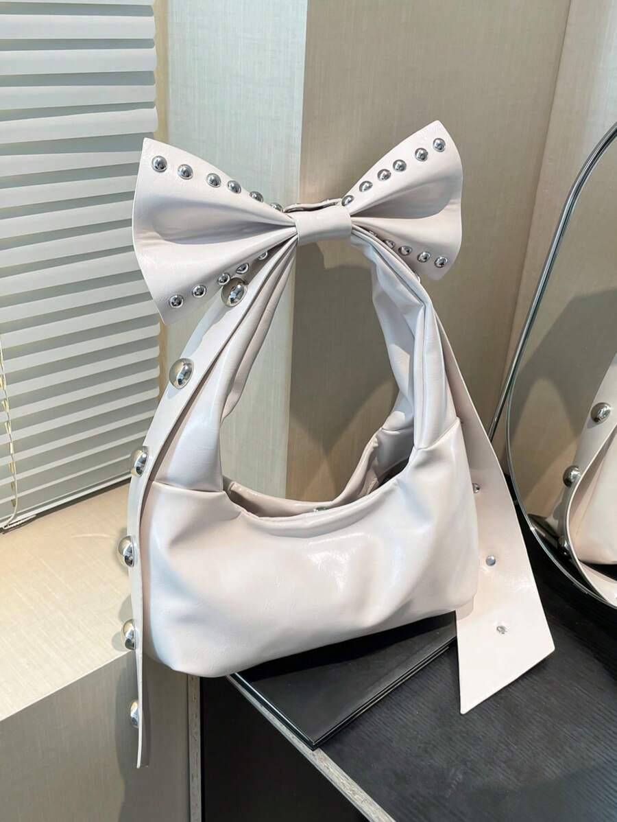 Add a dash of retro charm to your look with this Chic Black Retro Studded Bowknot Shoulder Bag. Its playful 2-in-1 crescent design lets you switch styles effortlessly, making it perfect for work, travel, or a casual day out. The studded bowknot adds a fun, edgy twist while the roomy interior keeps your essentials close and organized. Carry it your way and let this bag brighten every adventure!