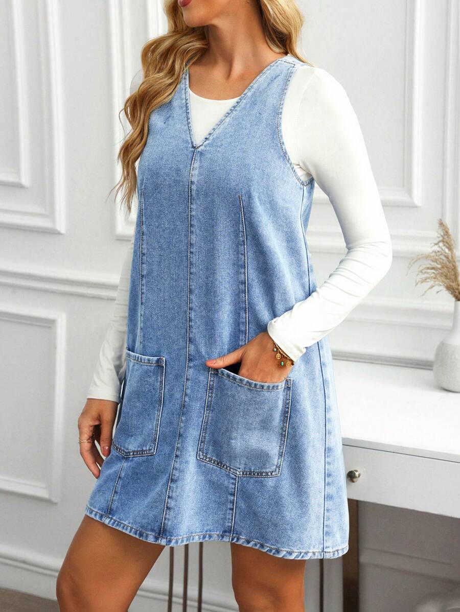 Front three-quarter view of light-wash blue A-line denim dress with oversized patch pockets