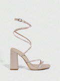 Worn close view of champagne chunky heel sandals with crystal toe strap and spiral ankle wrap