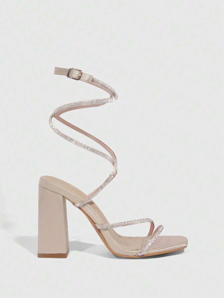 Worn close view of champagne chunky heel sandals with crystal toe strap and spiral ankle wrap