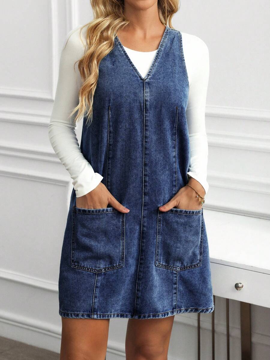 Full front view of deep blue washed denim pinafore mini dress with relaxed A-line silhouette