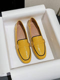 Side view of yellow slip-on loafer with black trim and gold buckle bit