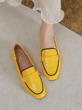 Hand-held view of yellow buckle loafer with black outsole