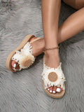Front and side on-foot view of fringed floral wedge sandals on gray faux fur