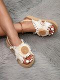 Crossed-leg view of cream slingback sandals with daisy appliques and low wedges