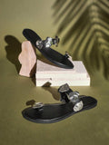 Side view of black toe-ring flat sandals with sculptural silver metal accents