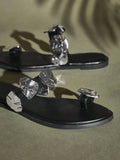 Close-up of black toe-ring flat sandal straps and sculptural silver metal details