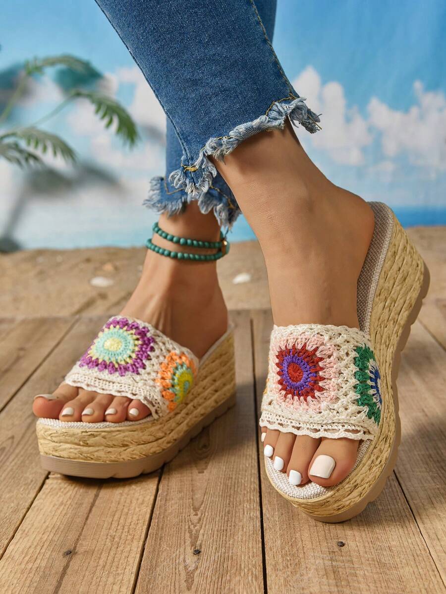 Front view of floral openwork wedge sandals worn with frayed jeans outdoors