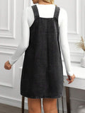 Back view of washed black denim pinafore dress showing square back and clean stitched hem