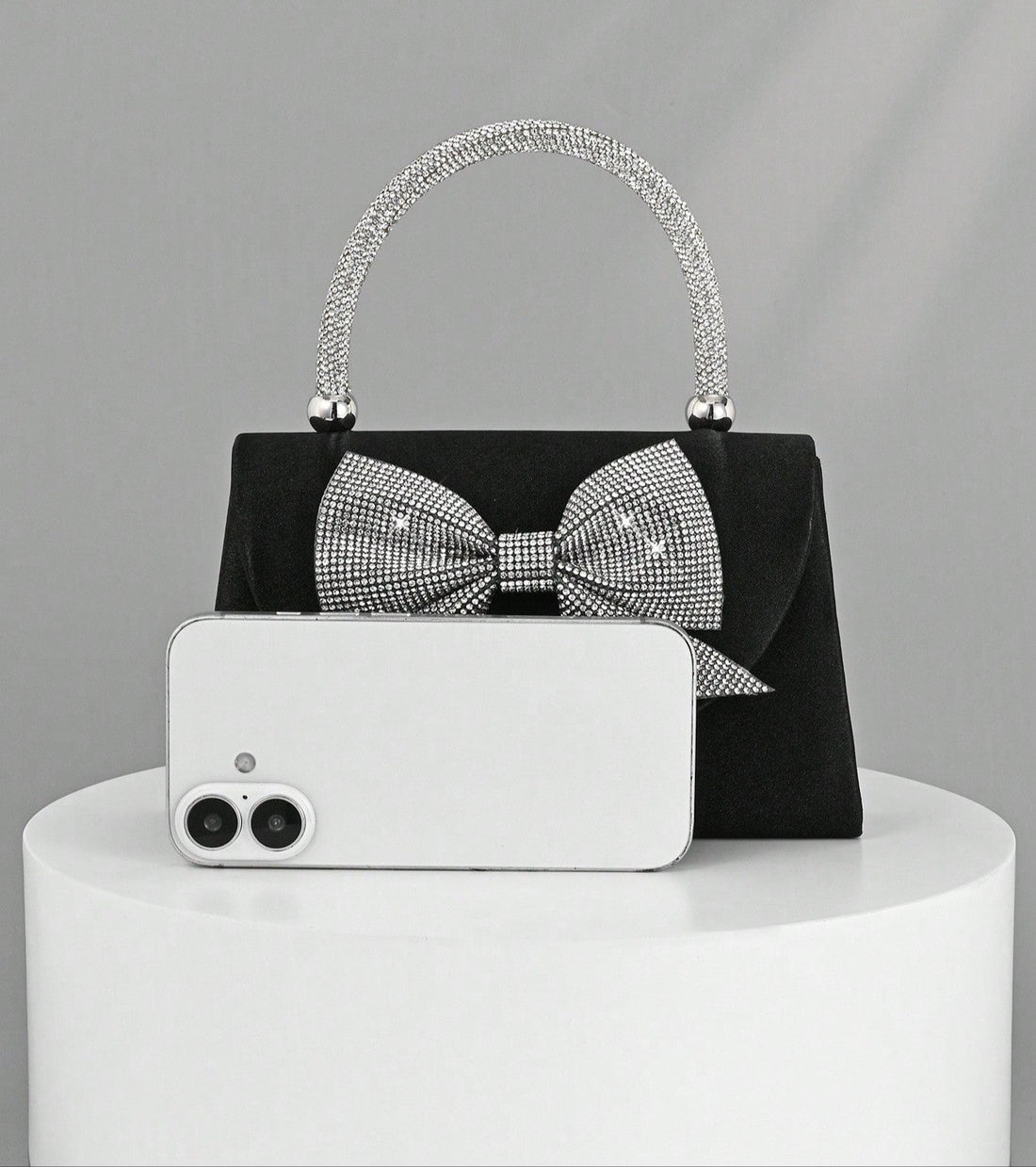 Step out in style with this Elegant Black Satin Clutch, featuring a sparkling rhinestone bowknot that adds just the right amount of glam. Perfect for parties and weddings, this luxury evening handbag is your go-to for keeping essentials close while turning heads. Its sleek design and dazzling detail make it a playful yet sophisticated accessory that brightens any outfit. Ready to dazzle? This clutch is your new best party buddy!