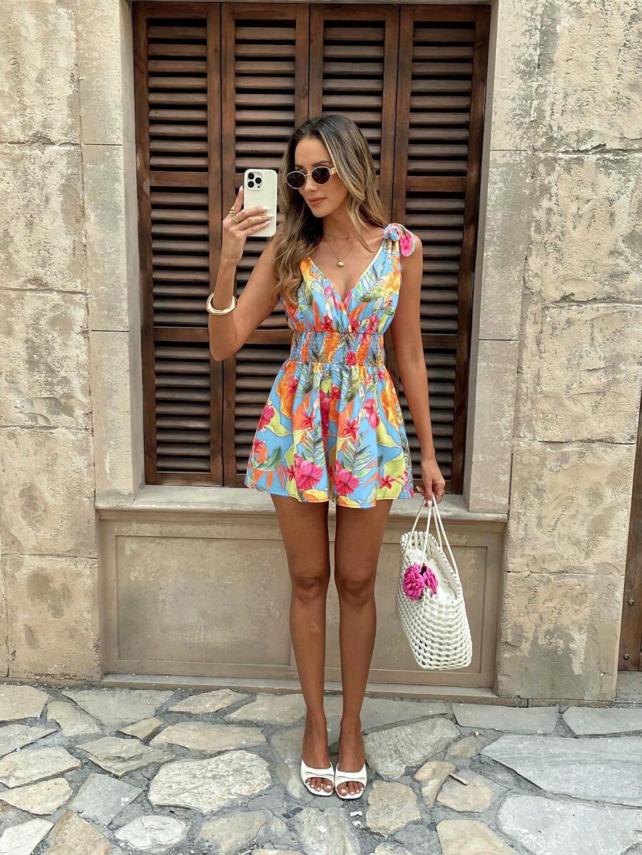 Full front view of light blue tropical floral romper with tie shoulders and smocked waist