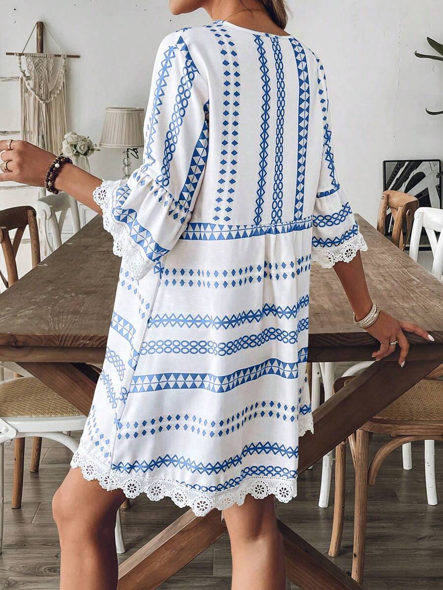 Front close view of blue geometric V-neck short dress with bell sleeves and white lace trim