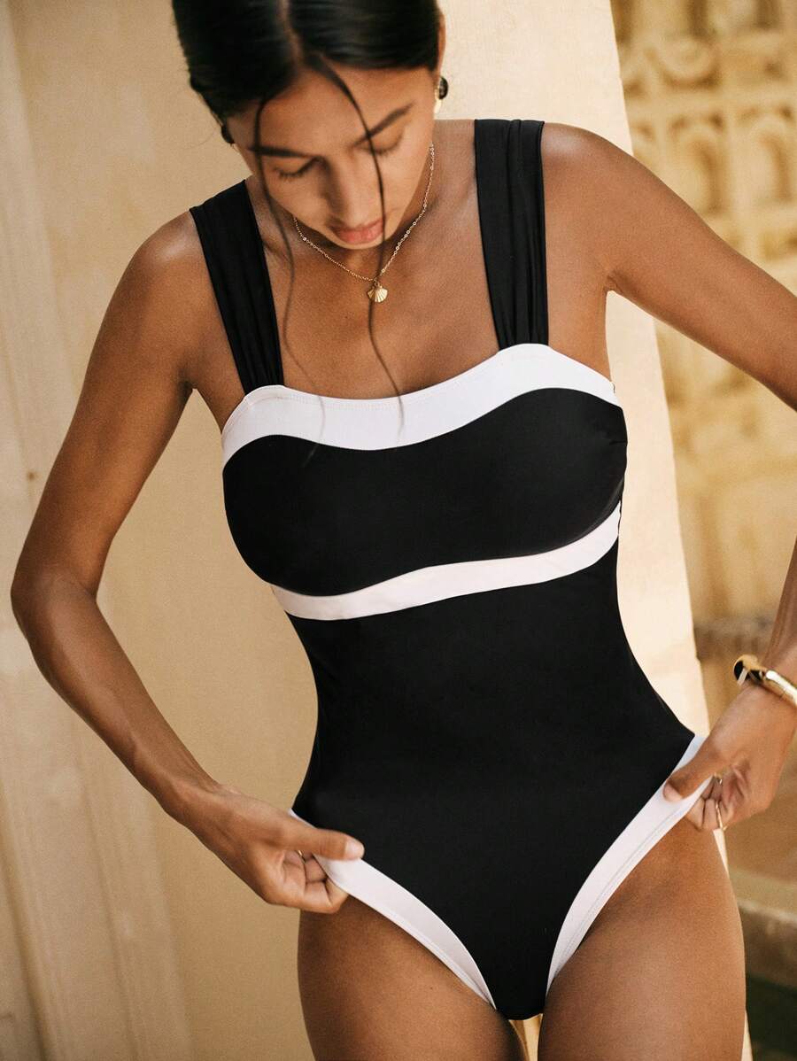 Make a statement at the beach with this sophisticated one-piece swimsuit featuring a striking black and white color block design. The elegant contrast creates a flattering silhouette while the timeless palette works with any beach look. Perfect for poolside lounging, ocean swims, or resort getaways, this chic piece combines style with comfort for your summer adventures.