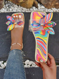 Rainbow swirl bow slide sandal worn on foot with metallic gold trim