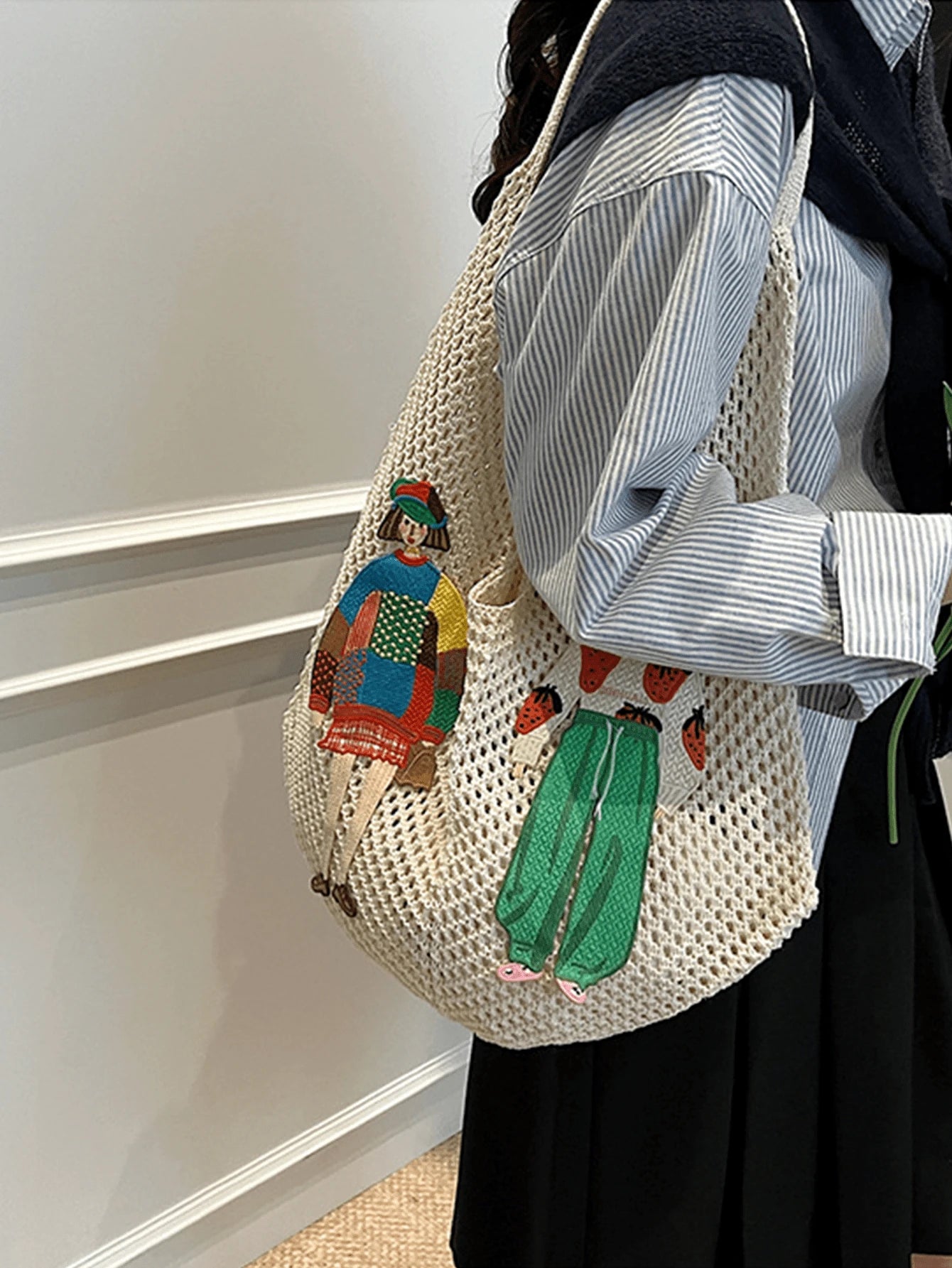 Cream crochet mesh shoulder bag worn with embroidered figure patches