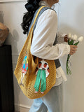 Mustard yellow crochet mesh shoulder bag worn with colorful embroidered figure patches