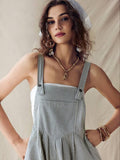 Close front view of gray pinstriped romper with square bib, buttoned straps and gathered waist