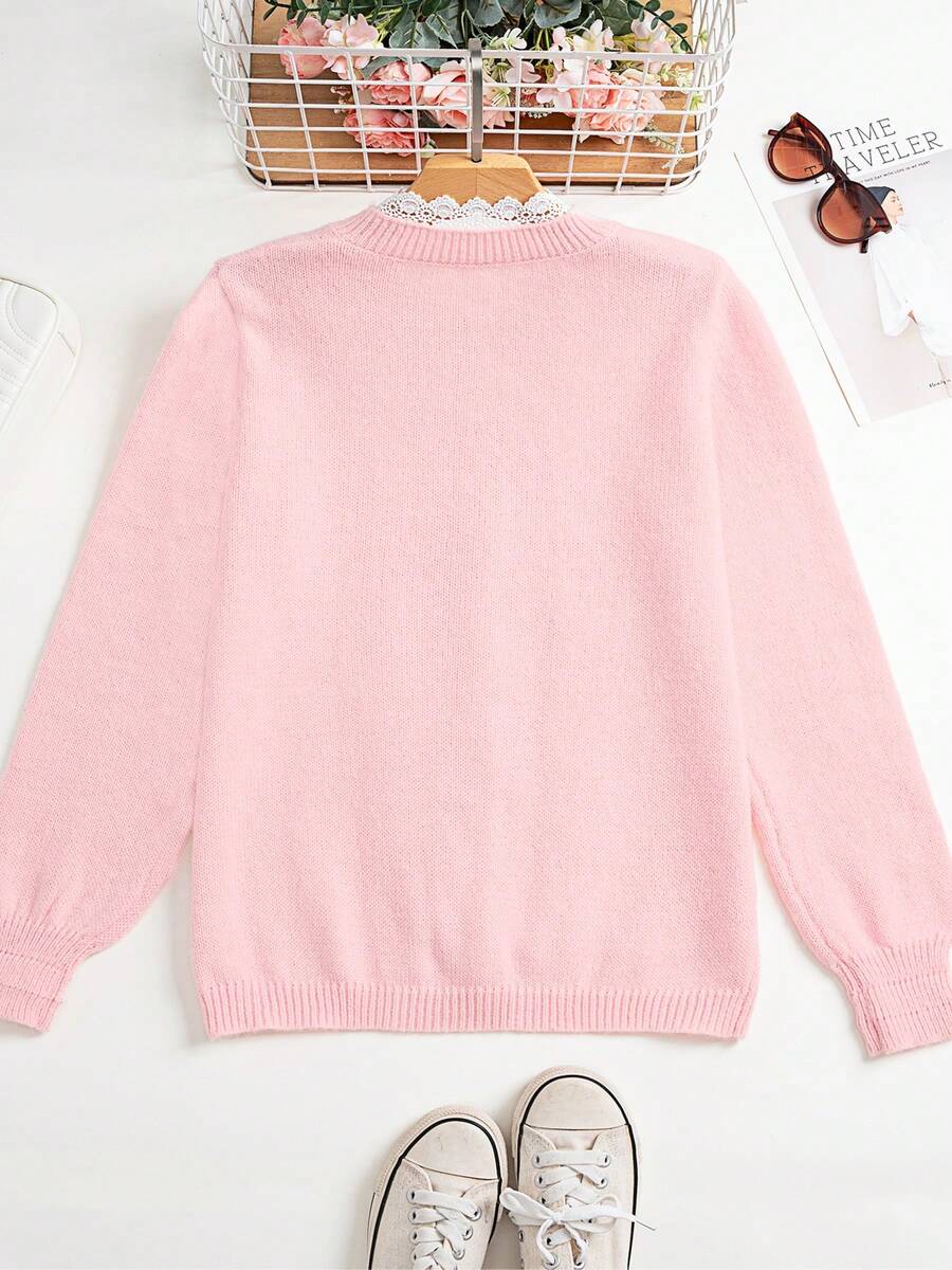 Front three-quarter view of baby pink lace knit cardigan styled with white trousers for daily wear