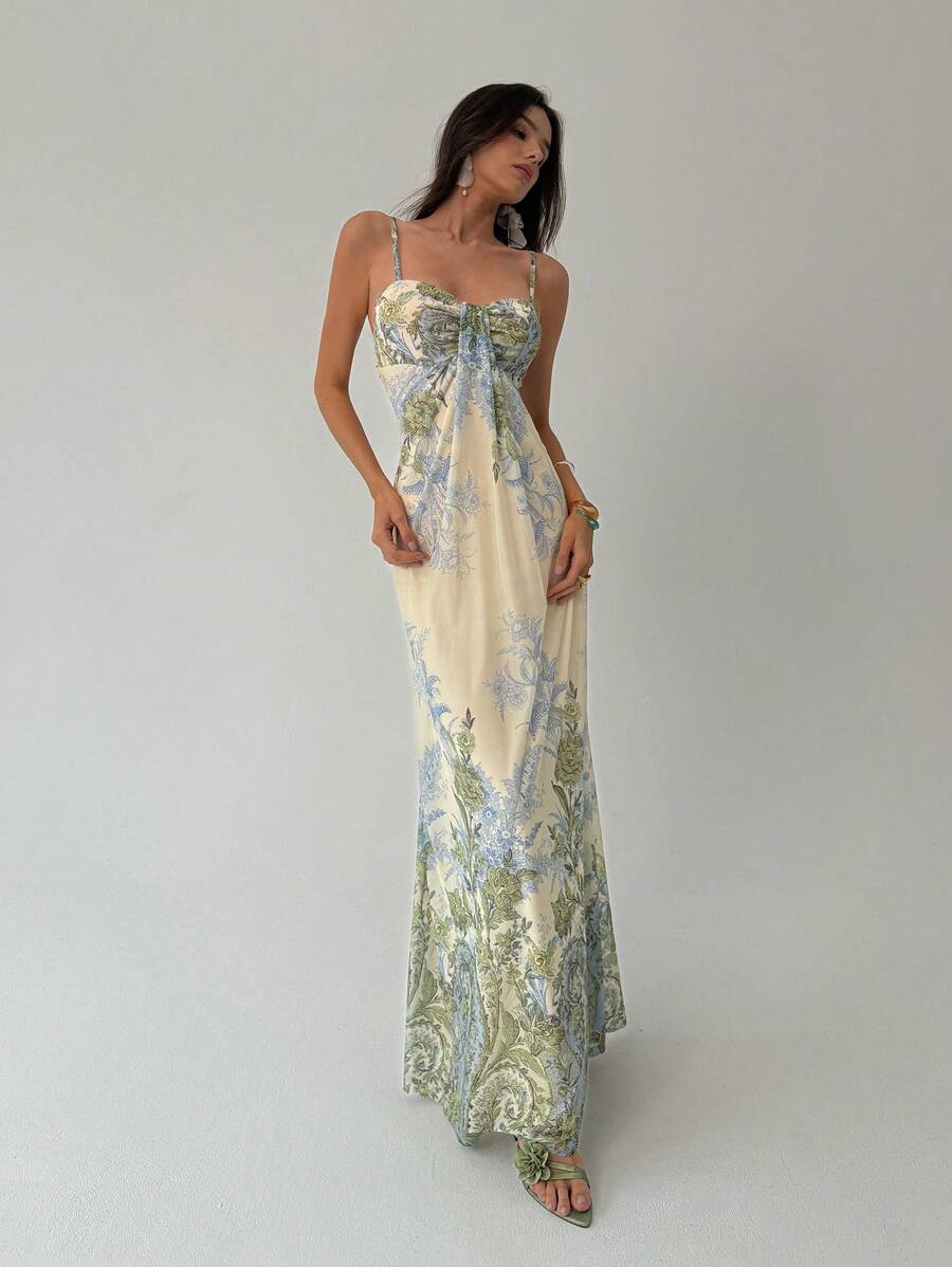 Front angled view of cream botanical print maxi dress with flowing floor length skirt