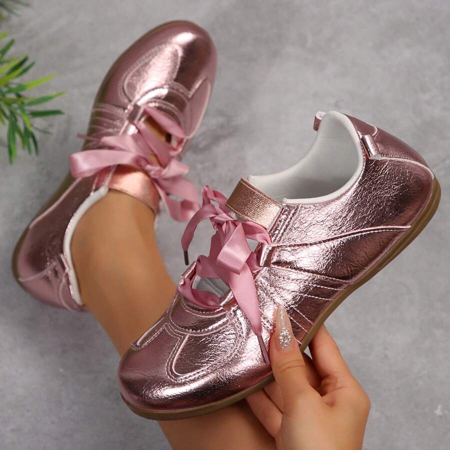 Top side view of metallic pink fashion sneaker with satin ribbon laces and instep strap