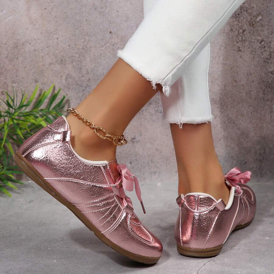 Rear side view of metallic pink low-top sneakers worn with white trousers