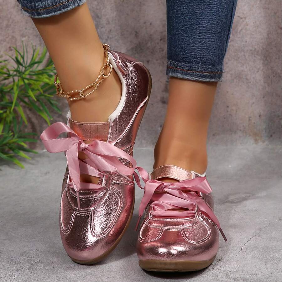 Front view of metallic pink round-toe sneakers worn with dark jeans