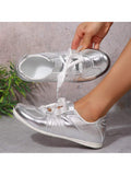 Top side view of metallic silver sneaker with satin ribbon laces and instep strap