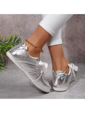 Rear side view of metallic silver low-top sneakers with clean white soles