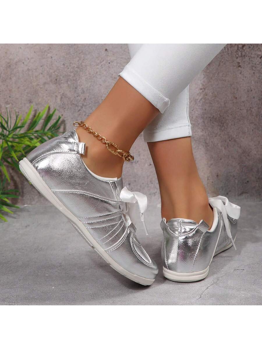 Rear side view of metallic silver low-top sneakers with clean white soles
