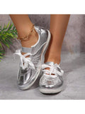 Front view of metallic silver round-toe sneakers worn with white trousers
