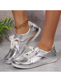 Front three-quarter view of metallic silver ribbon-lace sneakers with white soles