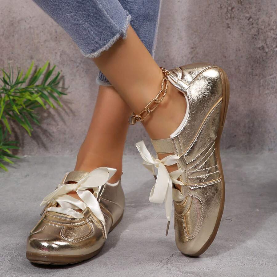 Rear side view of metallic gold fashion sneakers with gum soles and instep straps
