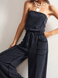 Close front view of charcoal strapless knit jumpsuit showing gathered waist and utility pockets